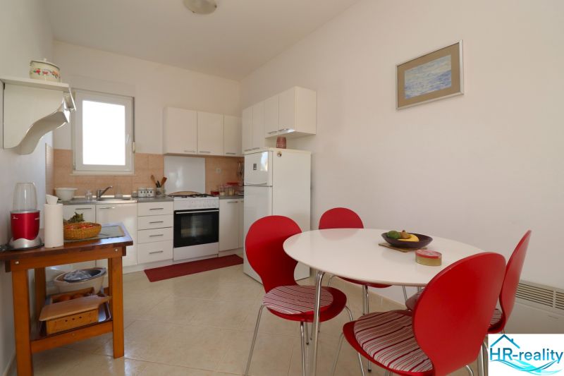 Chorvátsko, Vodice - zariadený bungalov, výhľad na more - Kuchyňa v rodinnom dome s bielym nábytkom a červenými stoličkami.