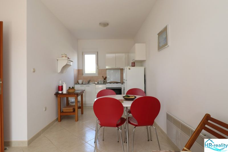 Chorvátsko, Vodice - zariadený bungalov, výhľad na more - Jedáleň s červenými stoličkami a bielou kuchyňou v rodinnom dome.