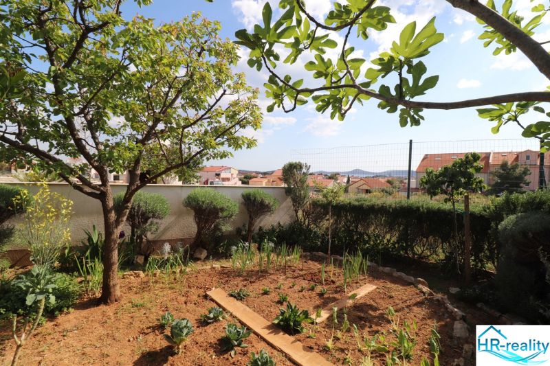 Chorvátsko, Vodice - zariadený bungalov, výhľad na more - Záhrada pri rodinnom dome vo Vodiciach, s výhľadom na okolité budovy a oblohu.
