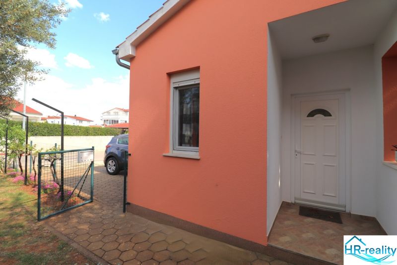Chorvátsko, Vodice - zariadený bungalov, výhľad na more - Rodinný dom vo Vodiciach s oranžovou fasádou a bielymi dverami pri vstupe.