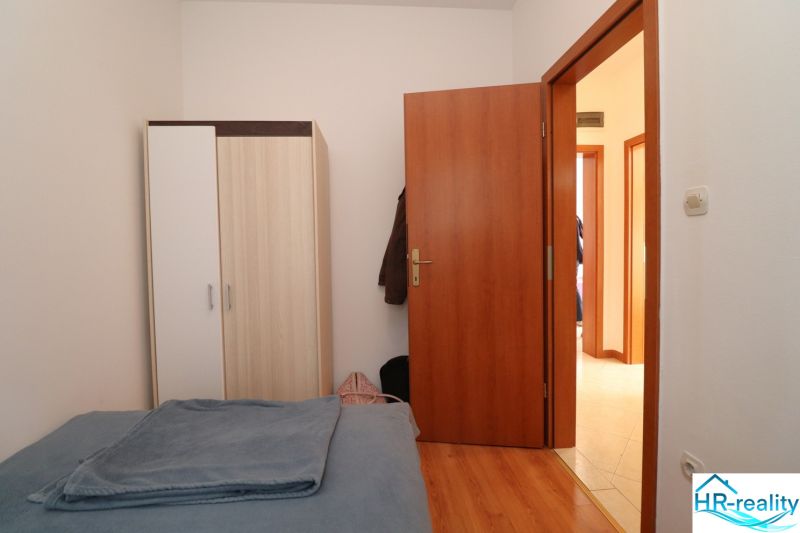 Chorvátsko, Vodice - zariadený bungalov, výhľad na more - Spálňa v rodinnom dome s posteľou, šatníkovou skriňou a podlahou s dreveným dekorom.