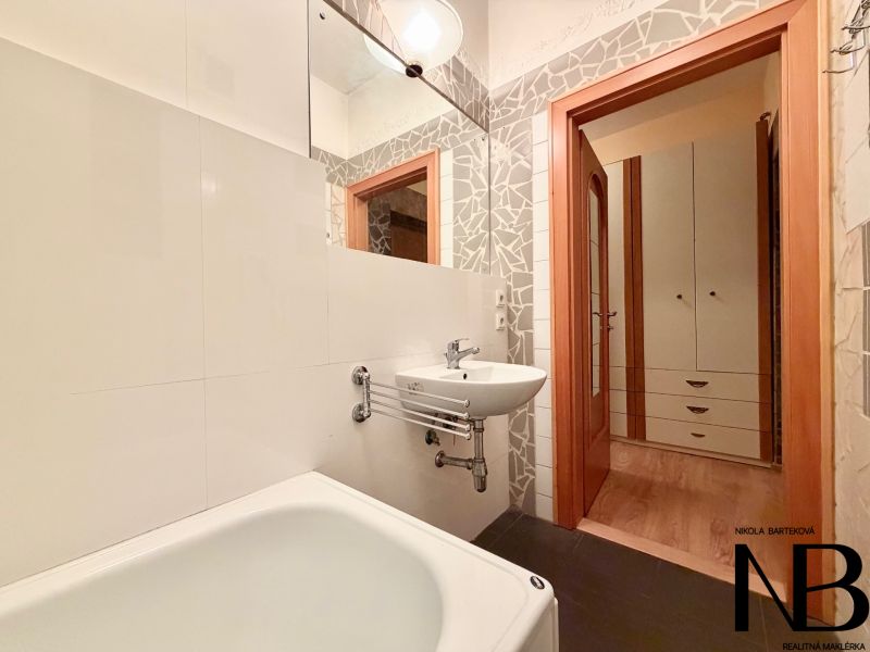 Na prenájom vybavený 2i byt, ul. Moravská, Bratislava - Kúpeľňa so svetlými obkladmi a vaňou v 2-izbovom byte, dvere vedú do chodby.