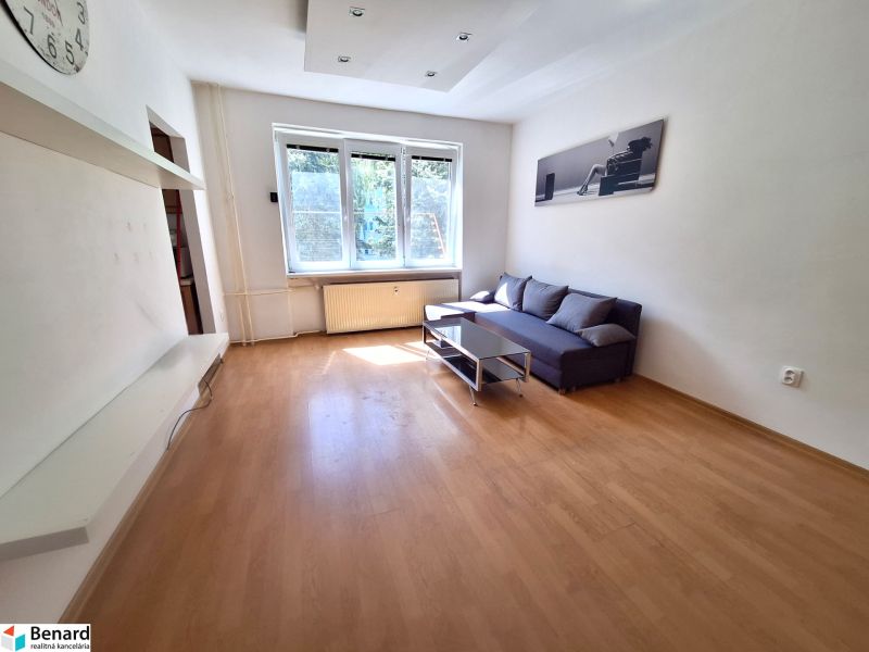 NA PRENÁJOM 1 IZBOVÝ TEHLOVÝ BYT, 34 M2, KOŠICE - ŠACA - Obývacia izba v 1-izbovom byte s podlahou s dreveným dekorom, pohovkou a stolíkom.