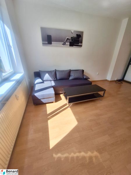 NA PRENÁJOM 1 IZBOVÝ TEHLOVÝ BYT, 34 M2, KOŠICE - ŠACA - Obývacia izba v 1-izbovom byte s pohovkou a podlahou s dreveným dekorom.