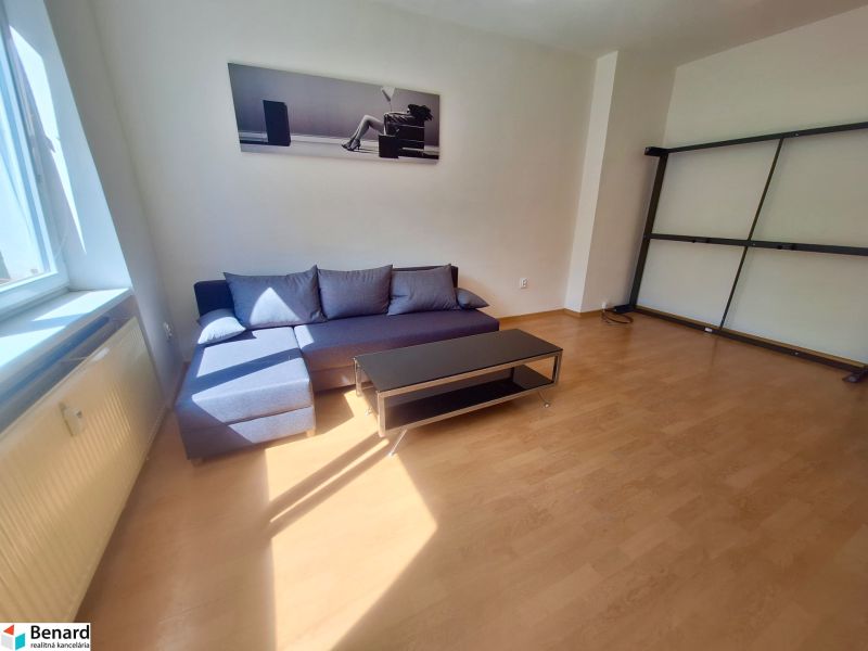 NA PRENÁJOM 1 IZBOVÝ TEHLOVÝ BYT, 34 M2, KOŠICE - ŠACA - Obývacia izba v 1-izbovom byte s gaučom a podlahou s dreveným dekorom.