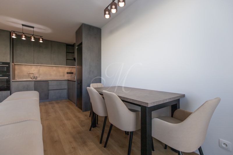 Moderný 2-izbový byt s balkónom, Ovocné sady - Kuchyňa v 2-izbovom byte so skrinkami, stolom a podlahou s dreveným dekorom.
