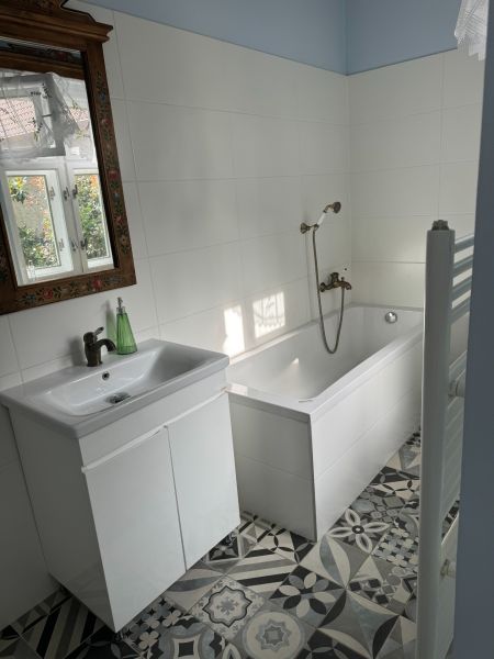 Štýlový 3-izbový rodinný dom po rekonštrukcii v obci Majcichov - Kúpeľňa v rodinnom dome s bielou vaňou, umývadlom a zdobeným zrkadlom.