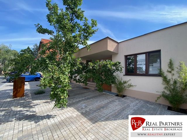 ,Prenájom moderný 3 izb. byt, Sološnícka ul,124 m2, Karlova Ves - Rodinný dom v Bratislave - Karlovej Vsi na Sološnickej ulici obklopujú stromy a dláždený chodník.