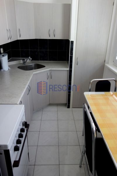 2-izbový byt, 51 m², samostatné izby, tichý, výhľad do zelene,K.Adlera - Kuchyňa 2-izbového bytu s bielymi skrinkami, sporákom a malým stolom.