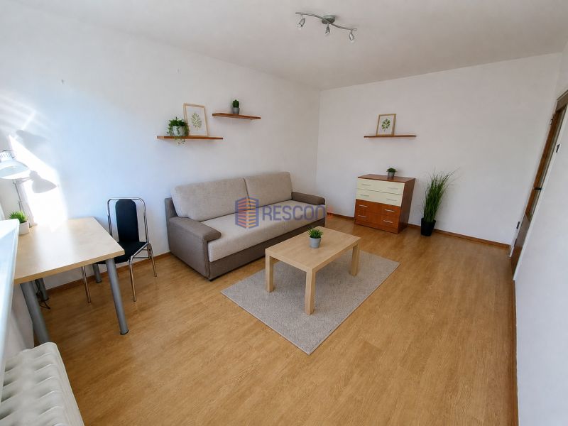 2-izbový byt, 51 m², samostatné izby, tichý, výhľad do zelene,K.Adlera - Obývačka s podlahou s dreveným dekorom, stolíkom a pohovkou v 2-izbovom byte.