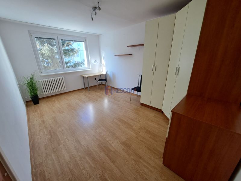 2-izbový byt, 51 m², samostatné izby, tichý, výhľad do zelene,K.Adlera - Izba s podlahou s dreveným dekorom, veľkými oknami, skriňou a písacím stolom.