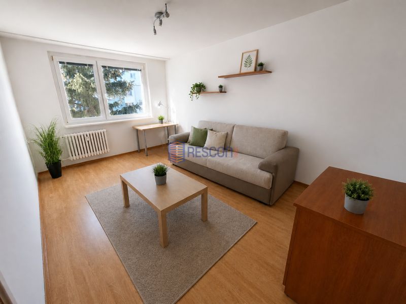 2-izbový byt, 51 m², samostatné izby, tichý, výhľad do zelene,K.Adlera - Obývacia izba v 2-izbovom byte s podlahou s dreveným dekorom a rozkladacou pohovkou.