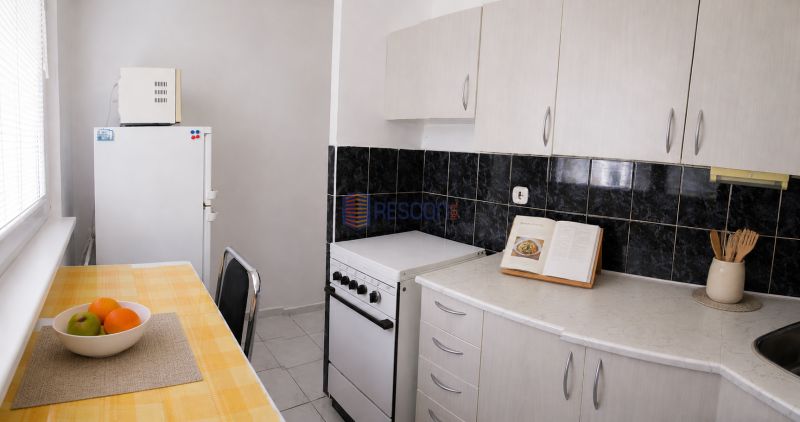 2-izbový byt, 51 m², samostatné izby, tichý, výhľad do zelene,K.Adlera - Kuchyňa v 2-izbovom byte s bielymi skrinkami a jedálenským stolom.