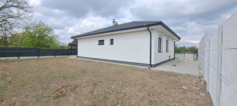 Novostavba pri jazere - 4 izbový rodinný dom v štandarde v obci Selice - Rodinný dom v Seliciach so záhradou a betónovým plotom v oblačnom počasí.