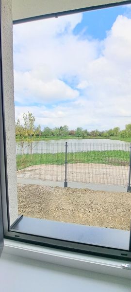 Novostavba pri jazere - 4 izbový rodinný dom v štandarde v obci Selice - Výhľad z rodinného domu v Seliciach na zarastenú vodnú plochu a plot.