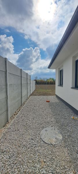 Novostavba pri jazere - 4 izbový rodinný dom v štandarde v obci Selice - Rodinný dom v Seliciach s betónovým plotom a štrkovou dlažbou na dvore.
