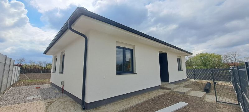 Novostavba pri jazere - 4 izbový rodinný dom v štandarde v obci Selice - Rodinný dom v Seliciach s bielou fasádou a čiernymi strešnými prvkami.