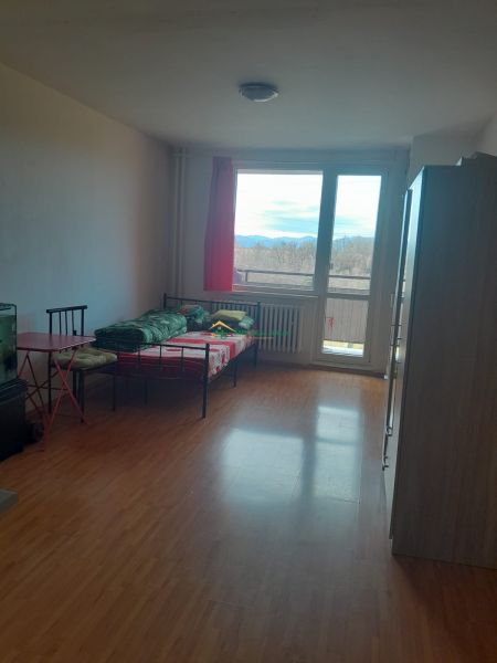 Predaj, Garsónka, Žiar nad Hronom  - Garsónka s pohovkou, podlahou s dreveným dekorom a výhľadom cez veľké okno.