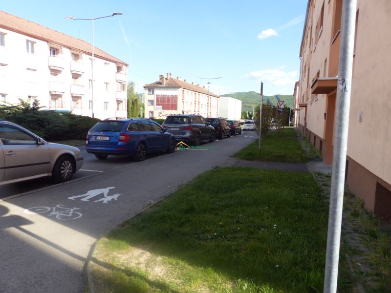 Predaj, 2 - izbový byt, Žiar nad Hronom - Parkovisko a budovy pri ceste v Žiari nad Hronom neďaleko 2-izbového bytu.