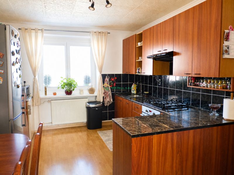 Predaj, 2 - izbový byt, Žiar nad Hronom - Kuchyňa v 2-izbovom byte s podlahou s dreveným dekorom a tmavými obkladmi.