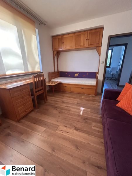Bývanie pod Tatrami: 3-izbový apartmán v Starej Lesnej - Izba v 3-izbovom byte s dreveným dekorom, skrinkami a gaučom.
