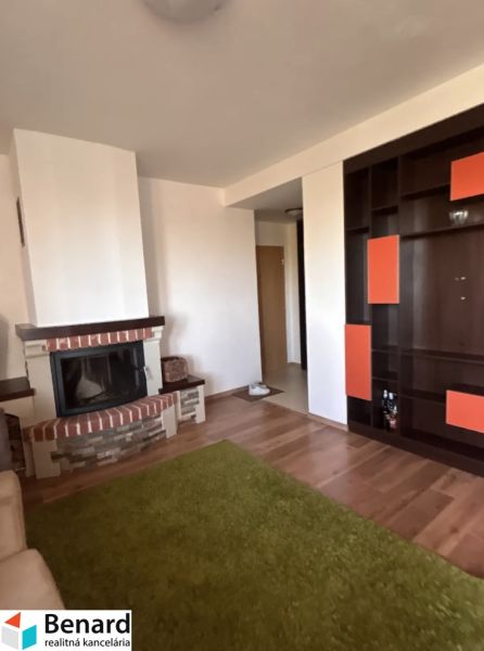 Bývanie pod Tatrami: 3-izbový apartmán v Starej Lesnej - Obývacia izba s kozubom, policovým systémom a podlahou s dreveným dekorom.