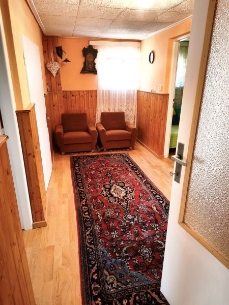 Priestranný 6-izbový rodinný dom v srdci Vysokej nad Kysucou – komfort - Rodinný dom so starožitným kobercom, podlahou s dreveným dekorom a oranžovými stenami.
