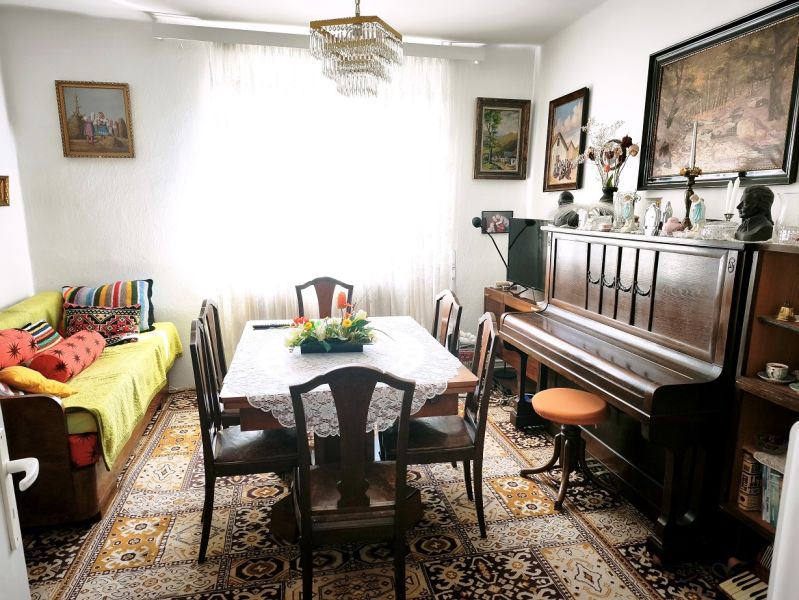 Priestranný 6-izbový rodinný dom v srdci Vysokej nad Kysucou – komfort - Obývacia izba v rodinnom dome s klavírom, kobercom a štýlovým nábytkom.