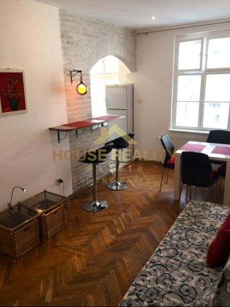 Prenájom 2 izbový byt, Murgašova ulica, Bratislava I. Staré Mesto - Obývacia izba 2-izbového bytu s podlahou s dreveným dekorom, barom a jedálenským stolom.