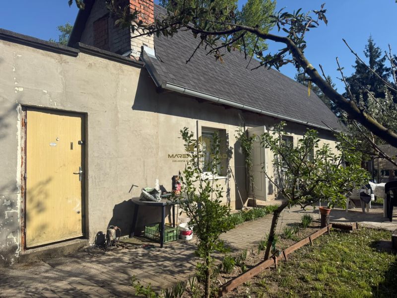 NA PREDAJ celoročná chata – Sekule (Šutrovňa), tiché prostredie - Pred chatou na ulici Sekule v Sekuliach sú stromy a záhradný nábytok.