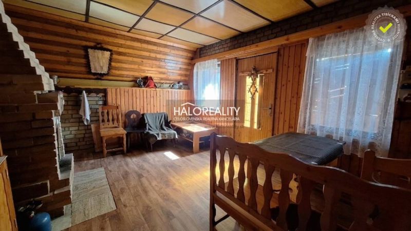 Predaj, chata Chyžné - EXKLUZÍVNE HALO REALITY - Interiér chaty s podlahou s dreveným dekorom a murovaným krbom, útulná atmosféra.