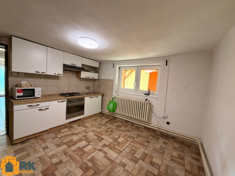 Predaj rodinného domu Piešťany - Kuchyňa v rodinnom dome s dlažbou a bielymi skrinkami.