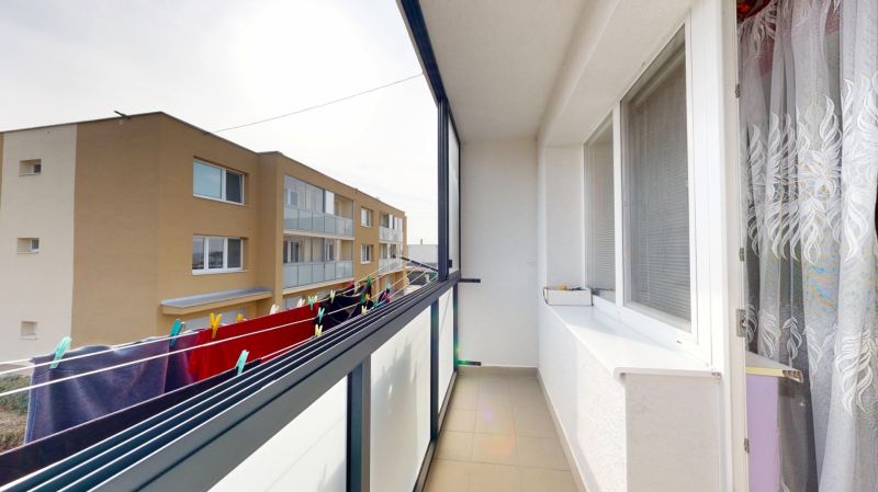 Štvorizbový byt  85 m2 s garážou a záhradou, Hlboké - okres Senica - Balkón 4-izbového bytu v Hlbokom s výhľadom na susednú budovu a sušiakom prádla.