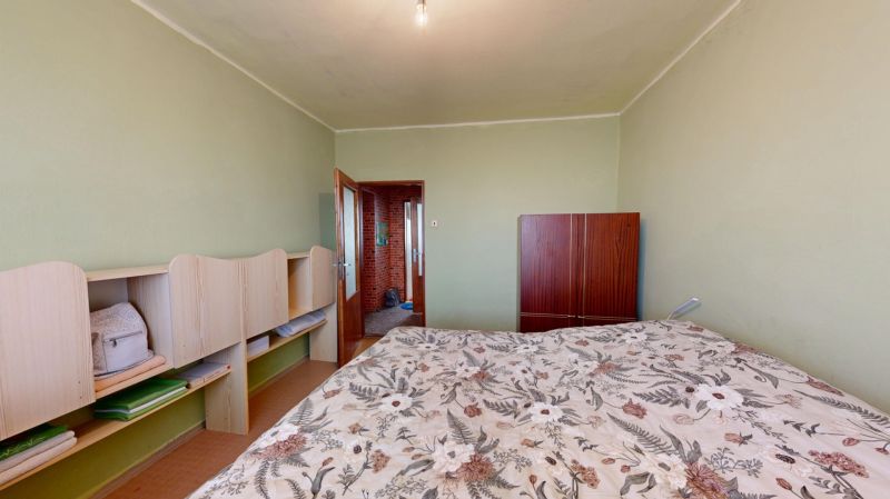 Štvorizbový byt  85 m2 s garážou a záhradou, Hlboké - okres Senica - Spálňa v 4-izbovom byte so svetlou stenou a posteľou s kvetinovým vzorom.
