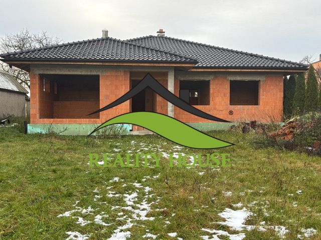 NOVOSTAVBA  - Rozostavaný bungalov v obci Dúbravka - Nedokončený rodinný dom v Dúbravke, s čiernou strechou a prázdnymi oknami, v zimnej záhrade.