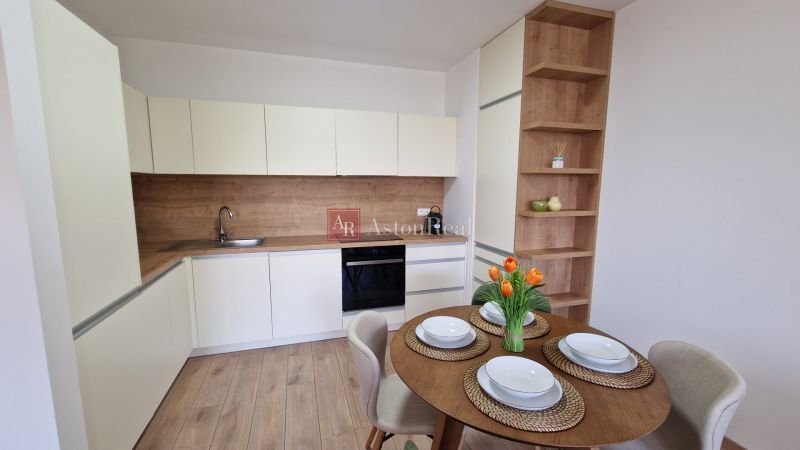 Exkluzívne 2 izbový byt POPRAD Karpatská, s garaž. st., balkón, 58 m2 - Kuchyňa v 2-izbovom byte so stolom a podlahou s dreveným dekorom.