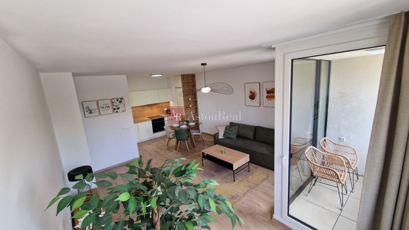 Exkluzívne 2 izbový byt POPRAD Karpatská, s garaž. st., balkón, 58 m2 - Interiér 2-izbového bytu s podlahou s dreveným dekorom, moderným nábytkom a balkónom.
