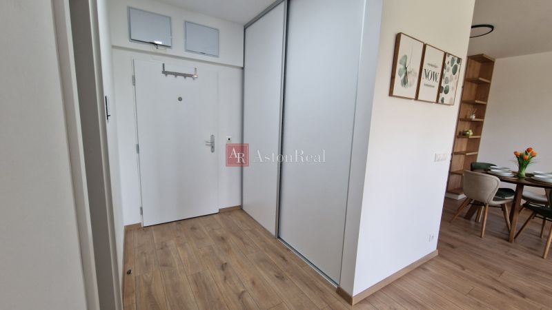 Exkluzívne 2 izbový byt POPRAD Karpatská, s garaž. st., balkón, 58 m2 - Interiér 2-izbového bytu s podlahou s dreveným dekorom, bielymi dverami a jedálenským kútom.
