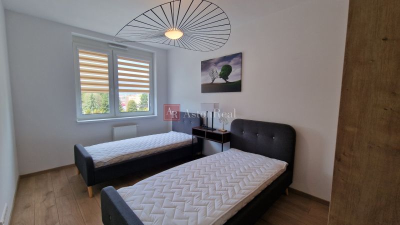 Exkluzívne 2 izbový byt POPRAD Karpatská, s garaž. st., balkón, 58 m2 - Spálňa v 2-izbovom byte s dvomi posteľami a podlahou s dreveným dekorom.