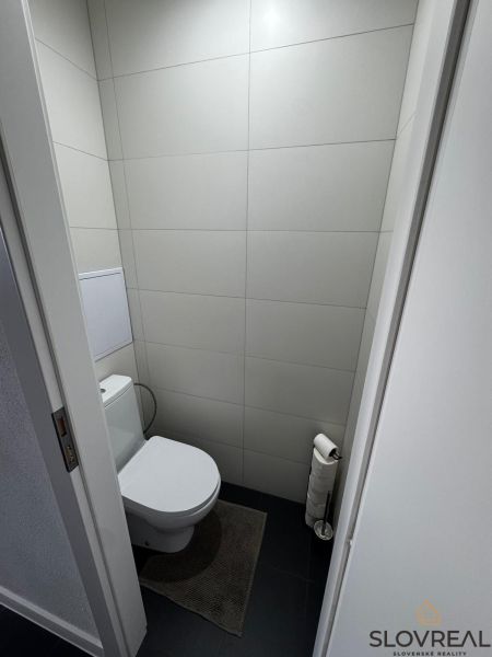Na predaj 3i byt Levice, Dopravná ul. - Toaleta v 3-izbovom byte s minimalistickými sivými obkladačkami a tmavou podlahou.