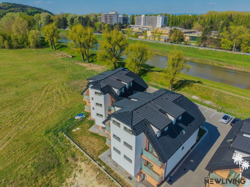 Na predaj 4iz. byt na Banke pri Piešťanoch - Bytový dom s čiernou strechou pri rieke na Moravanskej ulici v Banke.