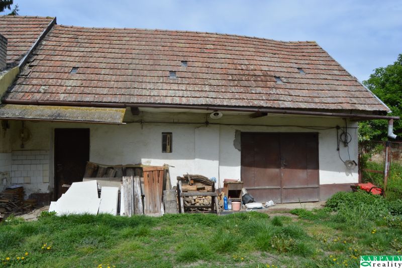Domček na chalupárčenie s veľkým pozemkom s termál kúpaliskom v obci! - Rodinný dom v Horných Salibách so starou strechou a neudržiavaným vonkajším priestorom.