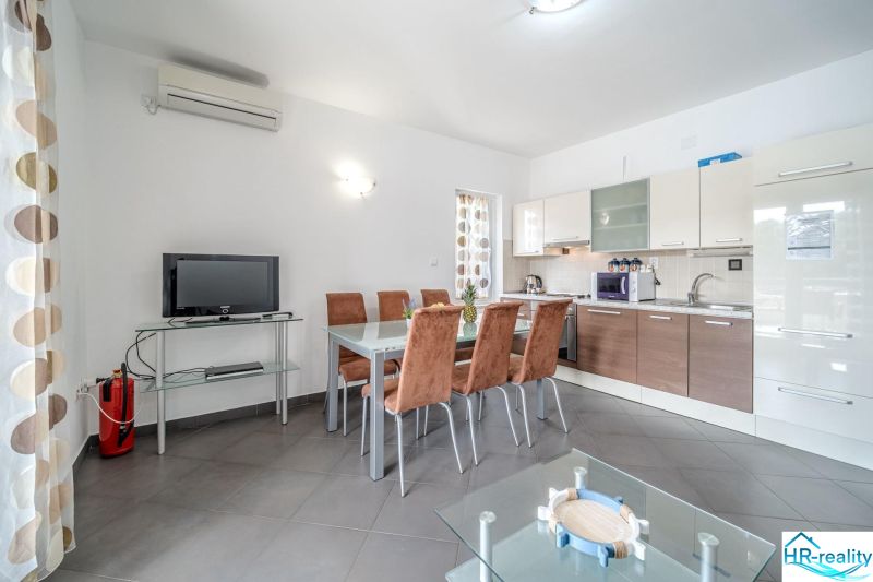 Brač(HR) - Apartmány v 1. rade u mora !!! - Svetlá kuchyňa s jedálenským stolom a televízorom v rekreačnom apartmáne.