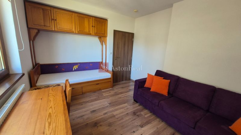 Investičný apartmán Vysoké Tatry - Stará Lesná s balkónom a park.miest - Rekreačný apartmán s pohovkou, posteľou, skriňou a podlahou s dreveným dekorom.