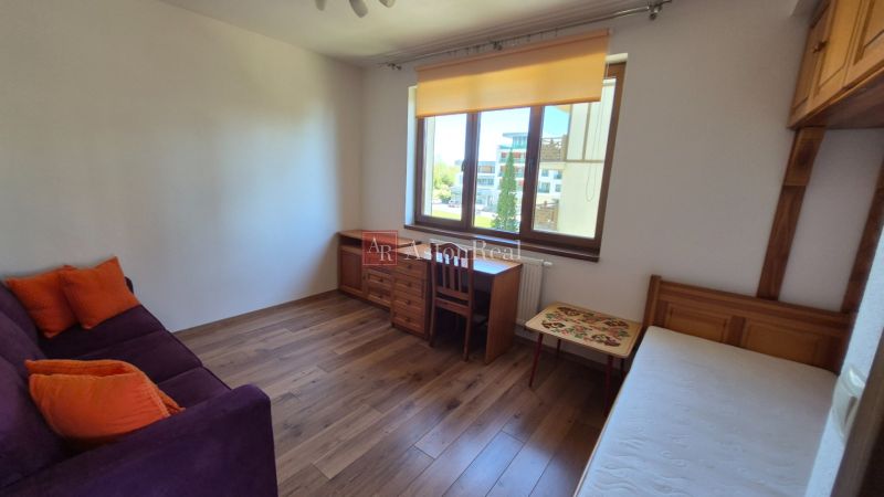 Investičný apartmán Vysoké Tatry - Stará Lesná s balkónom a park.miest - Izba v rekreačnom apartmáne s pohovkou, posteľou, písacím stolom a podlahou s dreveným dekorom.