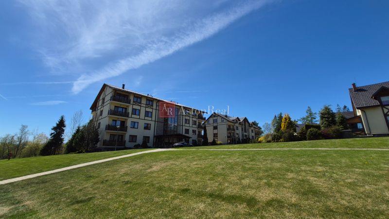 Investičný apartmán Vysoké Tatry - Stará Lesná s balkónom a park.miest - Rekreačný apartmán v Staréj Lesnej vo Vysokých Tatrách, obklopený trávnikom a stromami.