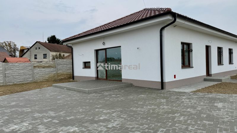 * novostavba moderného 4i domu, Vlčany, centrum - Rodinný dom na Hlavnej ulici vo Vlčanoch s bielou fasádou a dláždeným nádvorím.