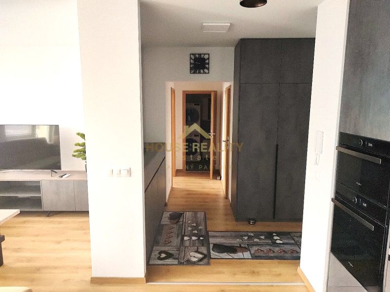Prenájom 2 izb. byt NOVOSTAVBA, Ivanská cesta, Bratislava II. Ružinov - Interiér 2-izbového bytu s podlahou s dreveným dekorom, televíziou a úložným priestorom.