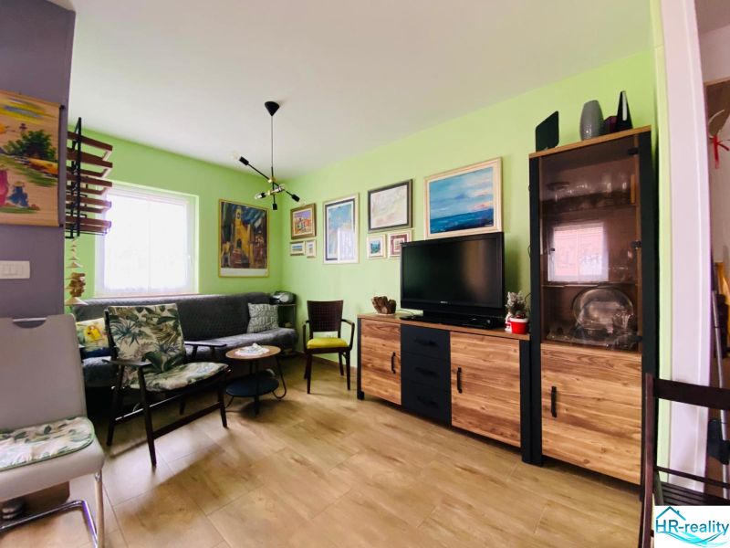 Brač(HR)–Apartmán s výhľadom na more - Obývacia izba s pohovkou, televízorom a podlahou s dreveným dekorom v Rekreačnom apartmáne.