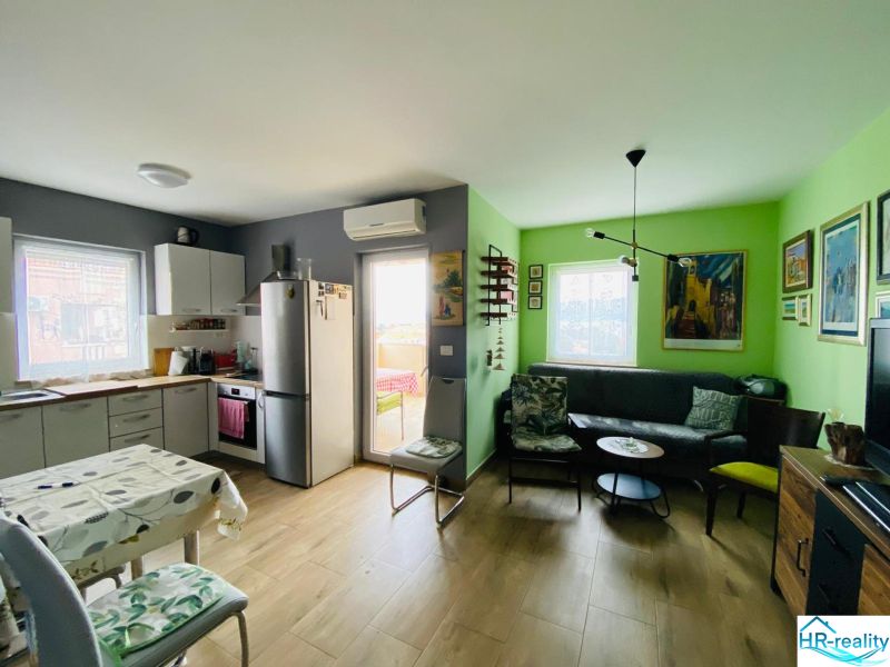 Brač(HR)–Apartmán s výhľadom na more - Rekreačný apartmán s kuchyňou, obývačkou, umením na stenách a podlahou s dreveným dekorom.
